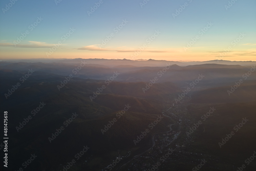 Aerial view of dark mountain hills at sunset. Hazy peaks and misty valleys in evening Aerial view of dark mountain hills at sunset. Hazy peaks and misty valleys in evening