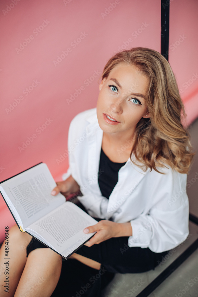 portrait of beautiful blonde woman holding a book and looking to the camera portrait of beautiful blonde woman holding a book and looking to the camera