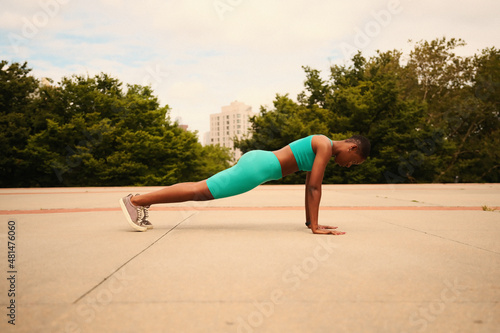 Athlete woman in sports clothing doing push-ups in park