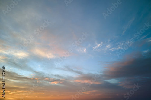 Bright colorful sunset sky with vivid smooth clouds illuminated with setting sun light spreading to horizon