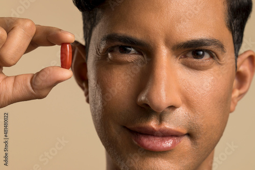 Close-up of man holding nutritional supplement capsule photo