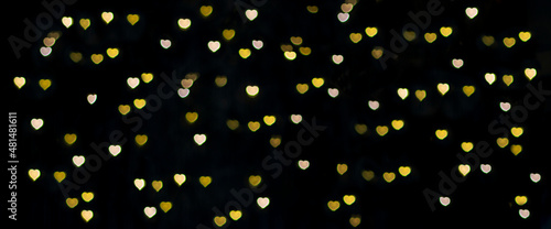 Golden bokeh in the form of hearts on a black background