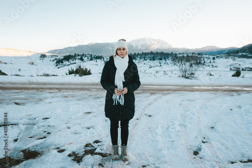 woman in hat and scarf outdoors in snow with mountain peak in the background