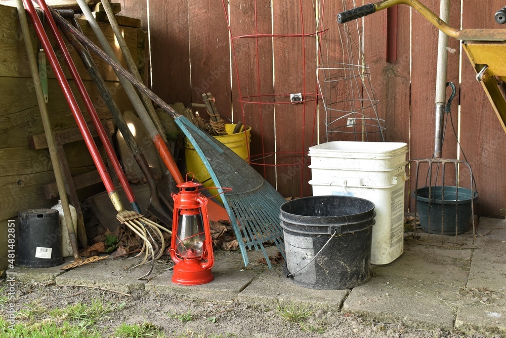Red lantern, old fashioned style. Sitting amid various garden tools. Red lantern, old fashioned style. Sitting amid various garden tools.