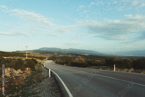 Bending country road with windmills on the hills © ardasavasciogullari