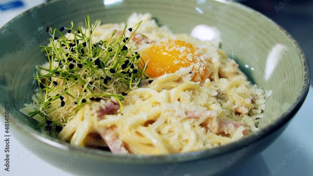 Delicious meal in a plate spinning. Tasty cooked pasta with yolk and green sprouts in the restaurant. Close-up. Pleasant appetite. Delicious meal in a plate spinning. Tasty cooked pasta with yolk and green sprouts in the restaurant. Close-up. Pleasant appetite.