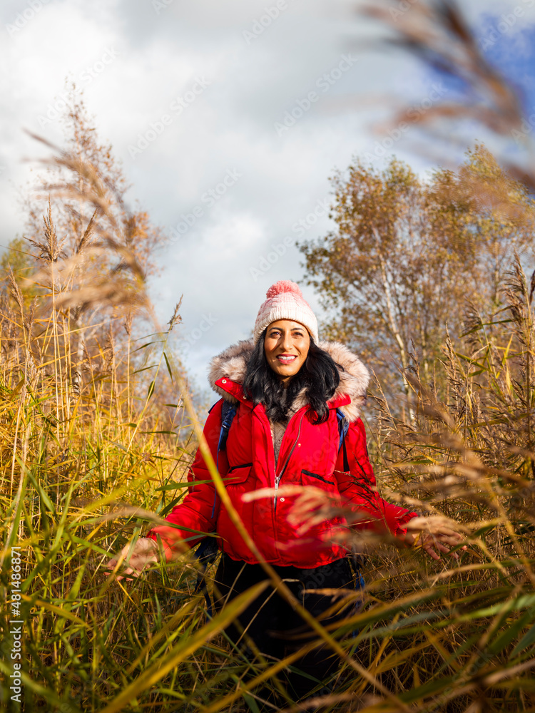 Smiling female hiker walking through tall grass Smiling female hiker walking through tall grass