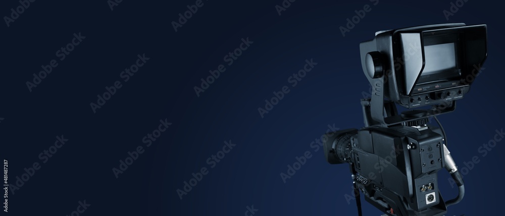 Digital film camera in the dark wall background. Video camera for film production,