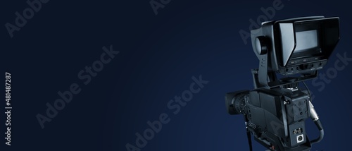 Digital film camera in the dark wall background. Video camera for film production,