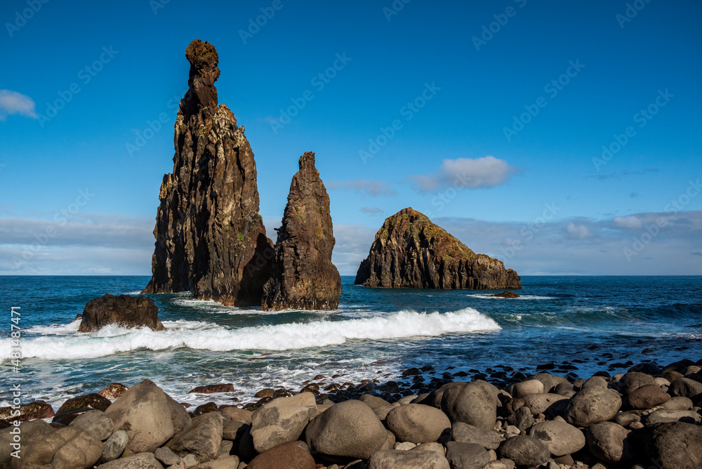 Beautiful coastal landscape with the “Ilheus da Ribeira da Janela” rock islets under a clear blue sky. The rock pinnacles are a famous landmark on the north coast of the island of Madeira, Portugal.