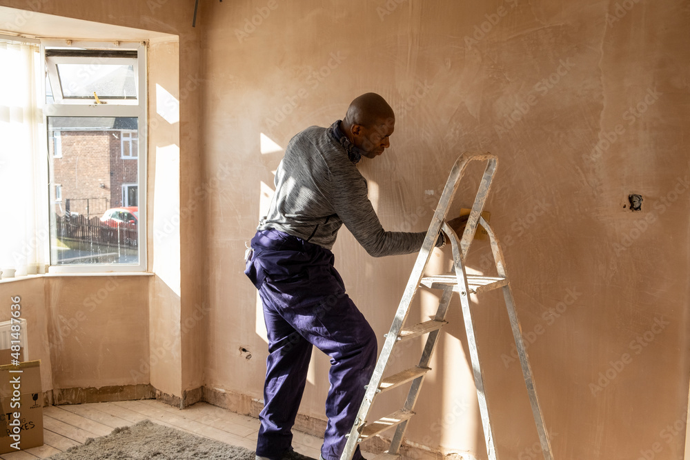 Man sanding wall in house Man sanding wall in house