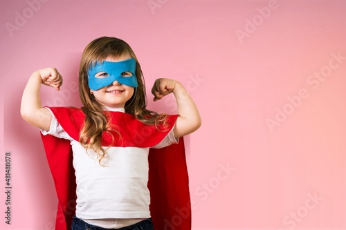 Portrait of little kid. Funny little power superhero kid showing muscles.