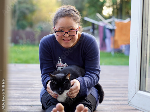 Portrait of girl with Down Syndrome sitting on patio with cat