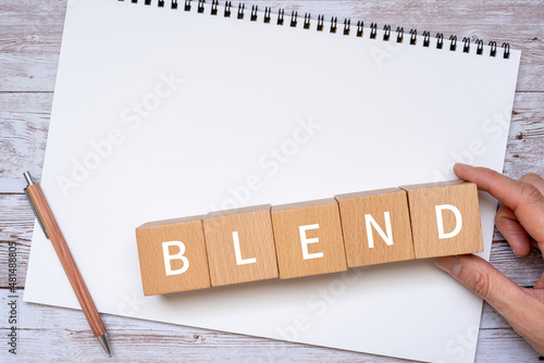 「BLEND」と書かれた積み木、ペン、ノート、人の手