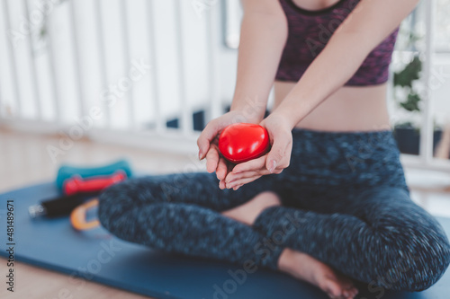 Happy sports woman holding red heart in hand. Medical cardio heart strength training lifestyle. Pretty female sports girl workout exercise. Cardiac healthy and well-being. healthy concepts