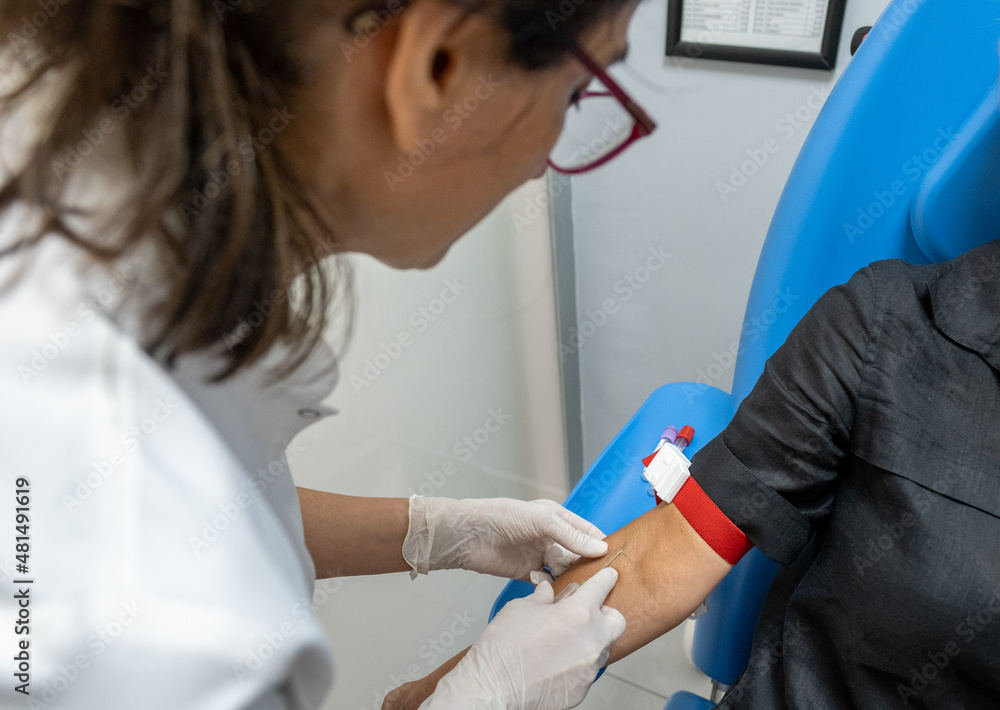 Female nurse taking blood sample with a syringe at a medical laboratory ...