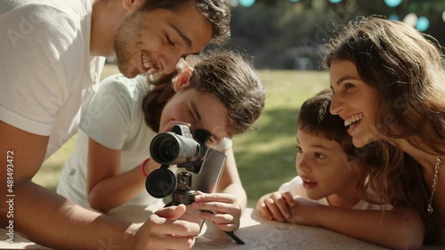 A happy family is excited at the park while the daughter looks through a monocular telescope.