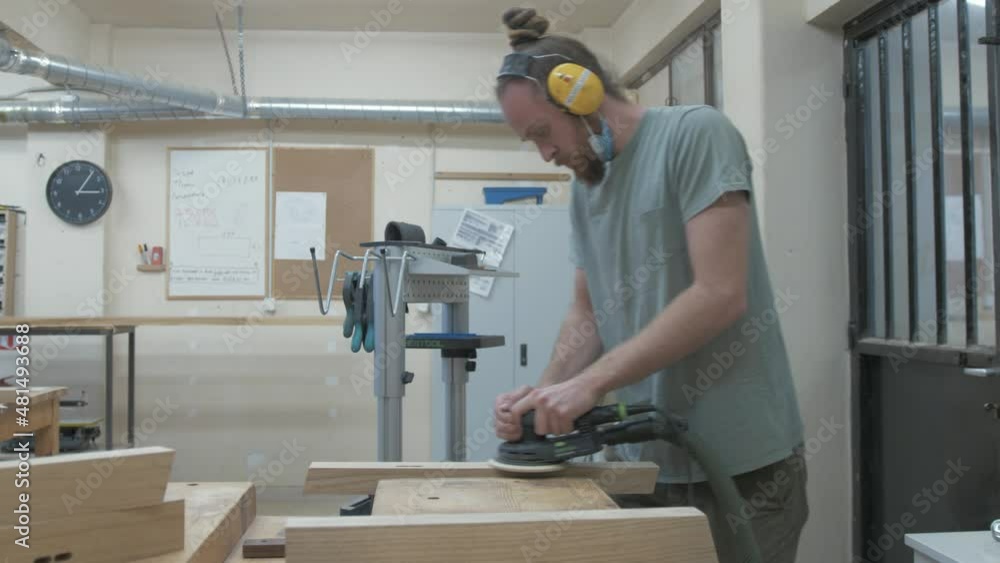 Carpenter sanding white oak bespoke furniture frames with orbital sander. MEDIUM SHOT Carpenter sanding white oak bespoke furniture frames with orbital sander. MEDIUM SHOT