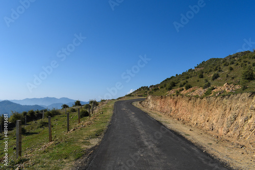 Straight tar asphalt road on top of mountain and greenery grass around countryside road