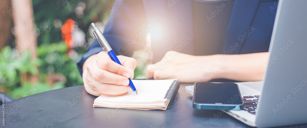 Woman hand writing on a notepad with a pen in the office.
