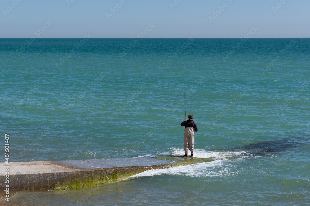 Man wearing waders fishing on the beach Man wearing waders fishing on the beach