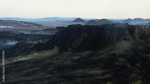 Black basalt solidified lava flow on slope of volcano with yellow mineral surface photo