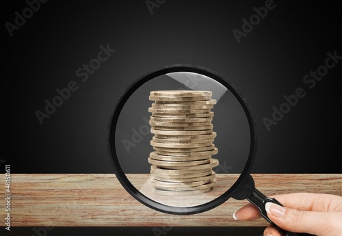 Focus on growing inflation concept. Growing columns of coins and magnifying glass