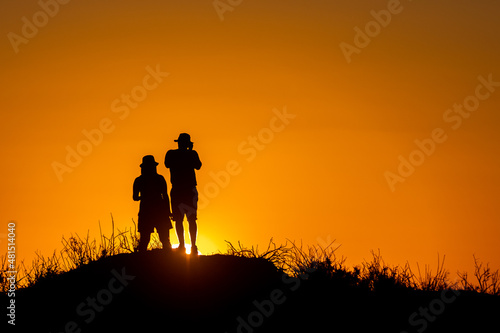 Silhouette of a man and a woman on a hill at sunset.