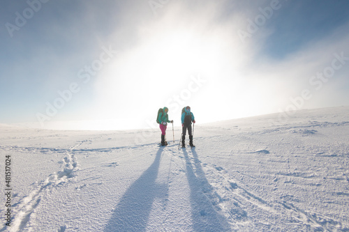 Two women walk in snowshoes in the snow