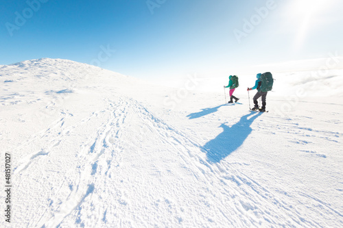 Two women walk in snowshoes in the snow