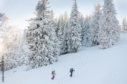 Two women walk in snowshoes on the mountain trail