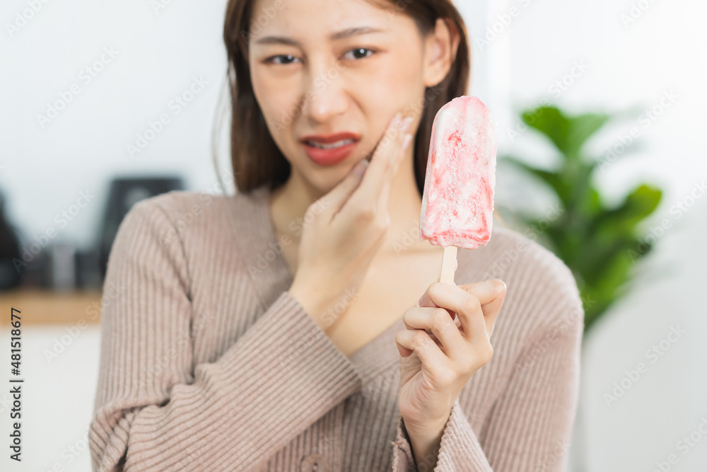 Health asian young woman touching cheek, expression, suffering from toothache, decay or sensitivity cavity molar tooth, teeth or inflammation eat cold ice cream at home. Sensitive teeth people. Health asian young woman touching cheek, expression, suffering from toothache, decay or sensitivity cavity molar tooth, teeth or inflammation eat cold ice cream at home. Sensitive teeth people.