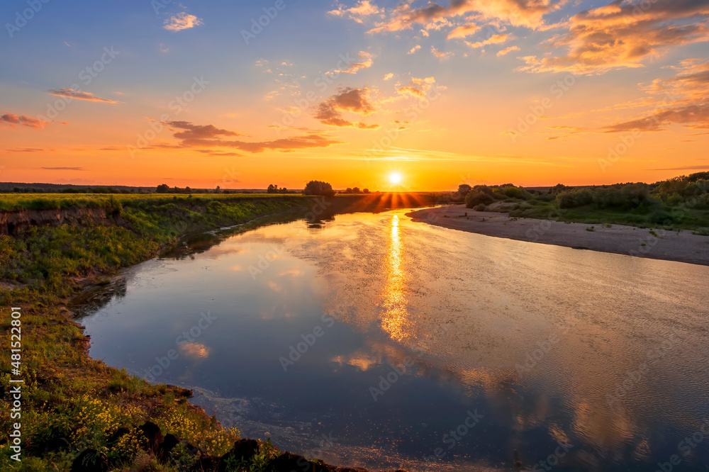 Obraz premium Amazing view at scenic landscape on a beautiful river and colorful sunset with reflection on water surface and glow on a background, spring season landscape