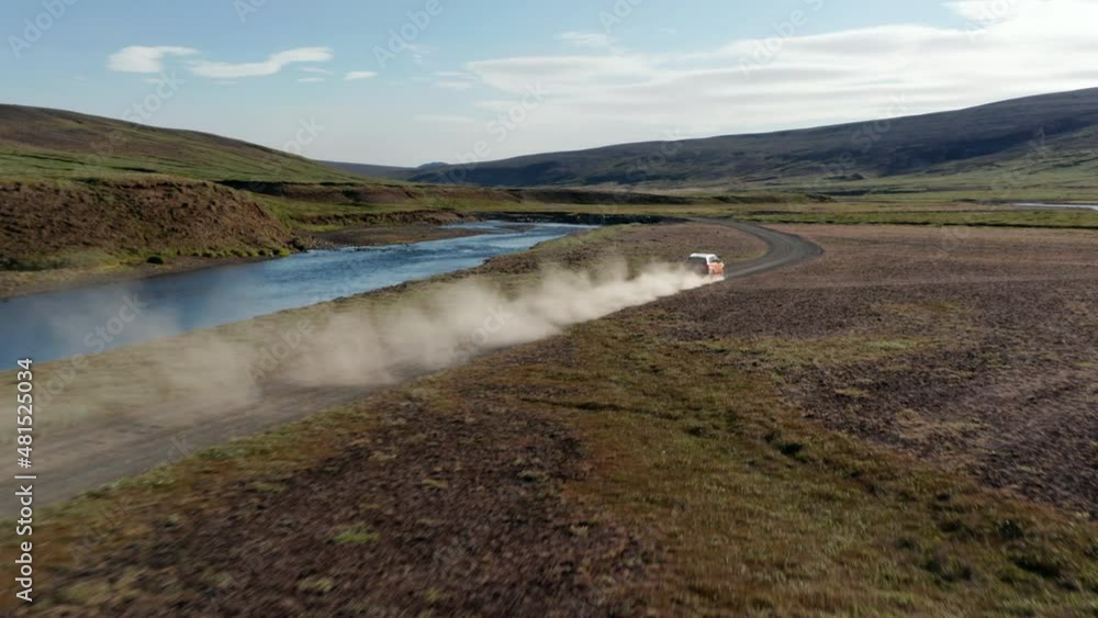 Forwards tracking of fast moving car leaving dust trace. Beautiful landscape scenery with river flowing along dirt road. Iceland Forwards tracking of fast moving car leaving dust trace. Beautiful landscape scenery with river flowing along dirt road. Iceland