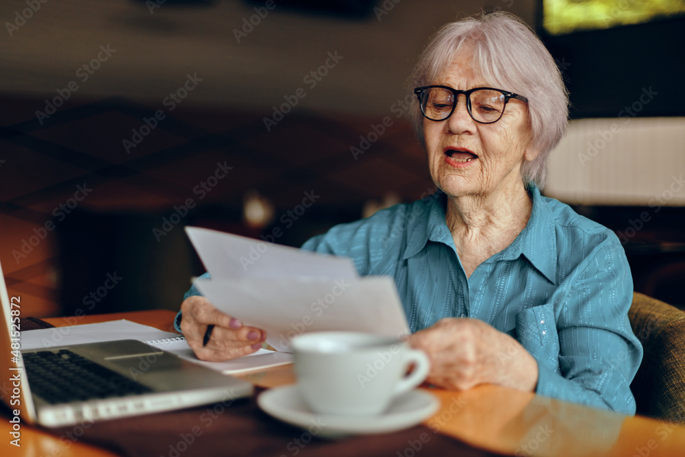 Portrait of an elderly woman sitting in a cafe with a cup of coffee and a laptop Freelancer works unaltered Portrait of an elderly woman sitting in a cafe with a cup of coffee and a laptop Freelancer works unaltered