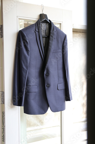 Stylish groom suit in dressing room indoors, hanging at the door.