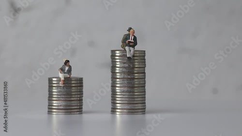 Miniature men and miniature women sitting on coins of different heights. Concept of gender pay gap.
