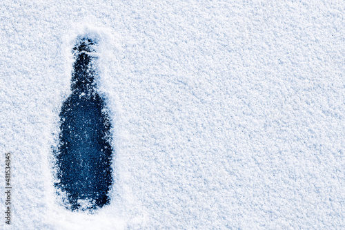 The bottle shape, drawn on a snow-covered surface on the ice of the winter river.