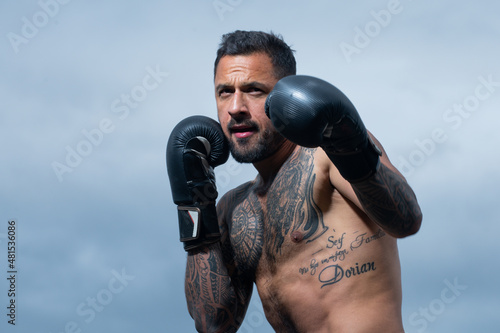 Boxer fighter training outdoors. Sportsman muay thai boxer fighting in gloves. Sporty man during boxing exercises. Strength, attack and motion concept. Boxer in movement. Strong muscular boxing man.