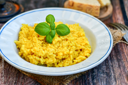  Italian creamy risotto milanese with parmesan cheese and fresh basil on rustic background