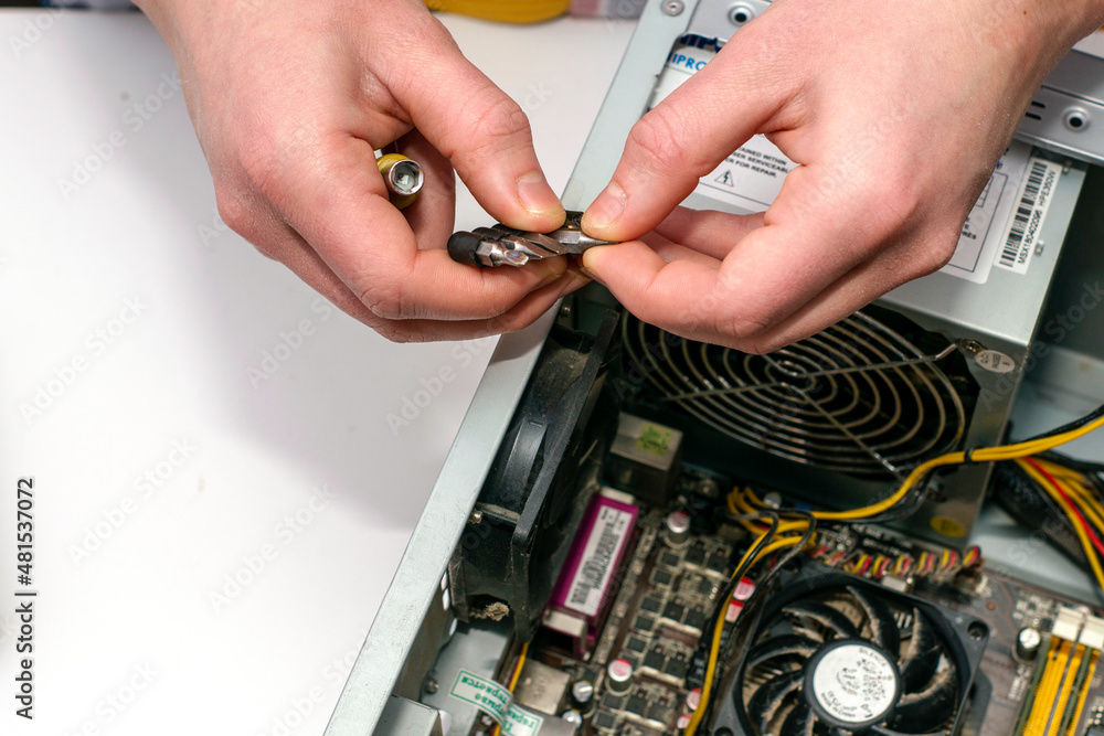 a master with a screwdriver in his hand repairs an old dusty computer