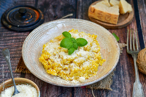  Italian home made creamy risotto milanese with parmesan cheese and fresh basil on rustic background