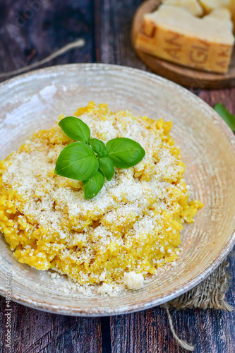  Italian home made creamy risotto milanese with parmesan cheese and fresh basil on rustic background