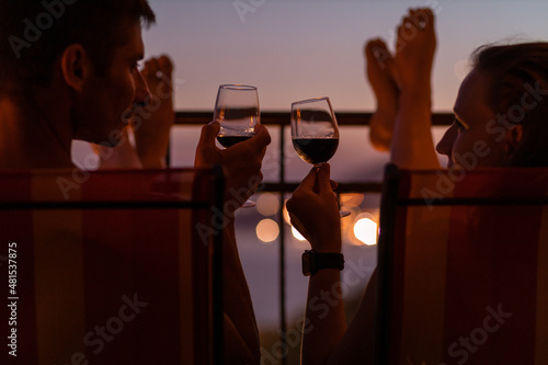 Romantic couple talking and have wine at sea view terrace at sunset. Valentine day image.