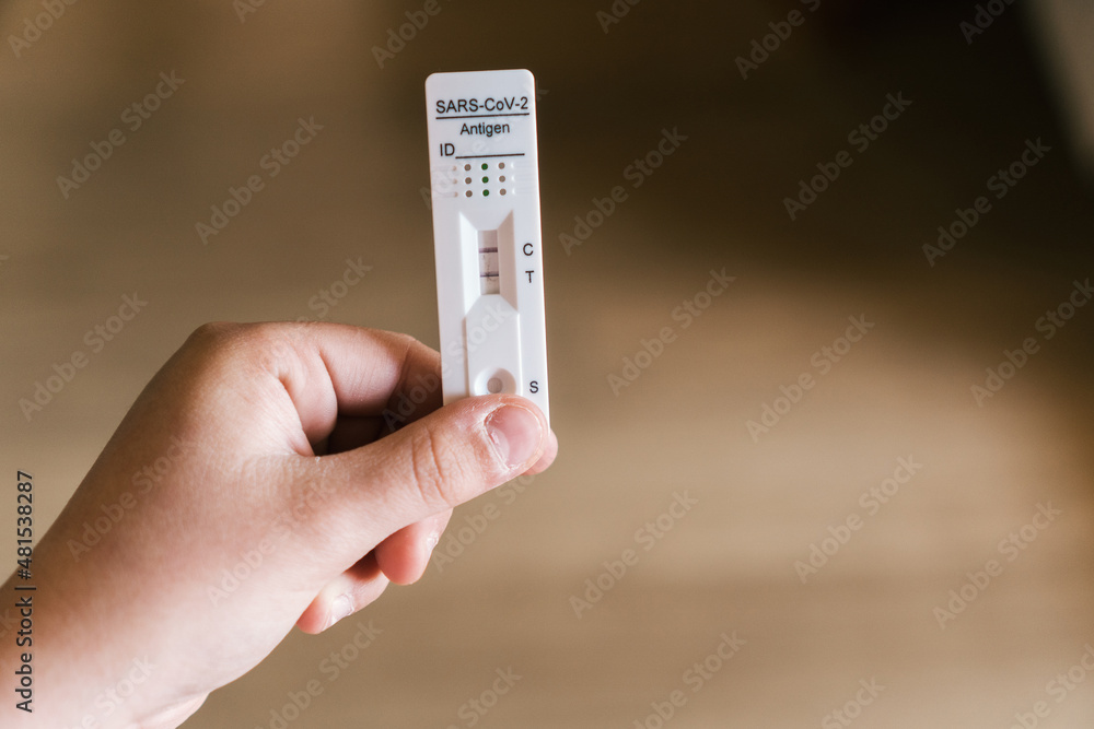 A person holds a positive covid-19 Antigen test in his hand. Home rapid test. Health and medicine concept. A person holds a positive covid-19 Antigen test in his hand. Home rapid test. Health and medicine concept.
