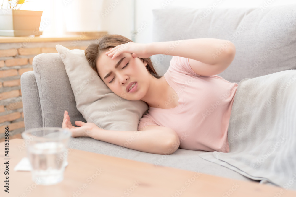 Portrait of Asian woman is holding their hand from headache lying on sofa, Young beautiful Asian woman on sofa having headache / migraine / stress / sick Portrait of Asian woman is holding their hand from headache lying on sofa, Young beautiful Asian woman on sofa having headache / migraine / stress / sick