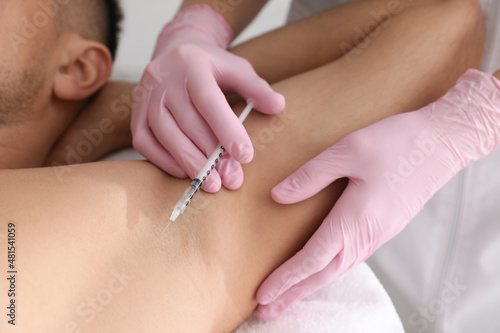 Cosmetologist injecting man s armpit  closeup. Treatment of hyperhidrosis