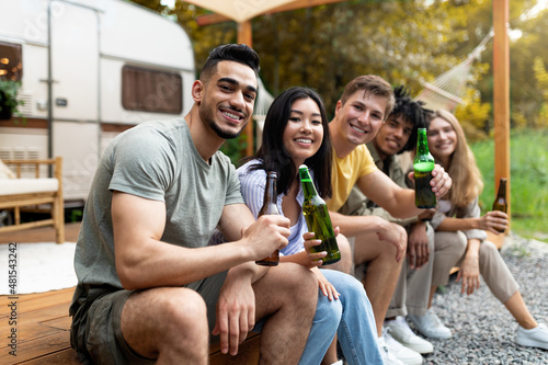 Photography Diverse young friends having party near RV outdoors, drinking beer, communicatin