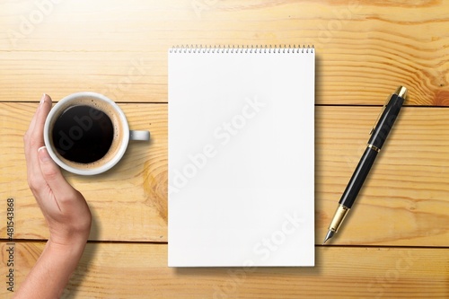 Writing in a planner and a coffee cup or tea on the desk