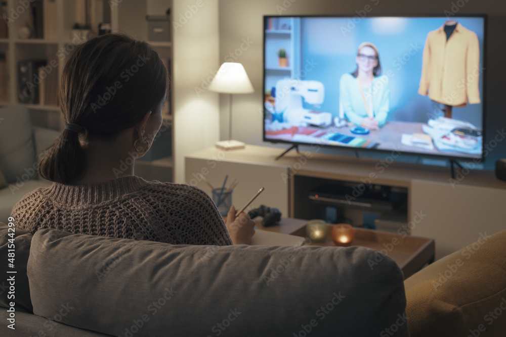 Woman watching a sewing course on TV Woman watching a sewing course on TV